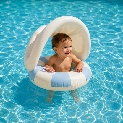 Bébé installé dans une bouée gonflable avec pare-soleil bleu dans une piscine