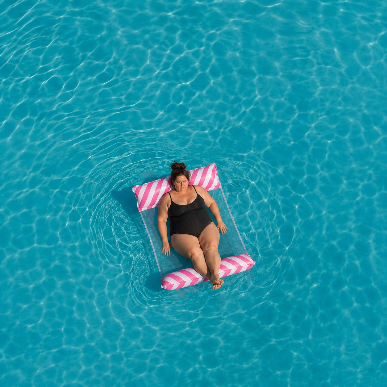 Hamac de piscine gonflable rose vu de dessus dans une eau turquoise